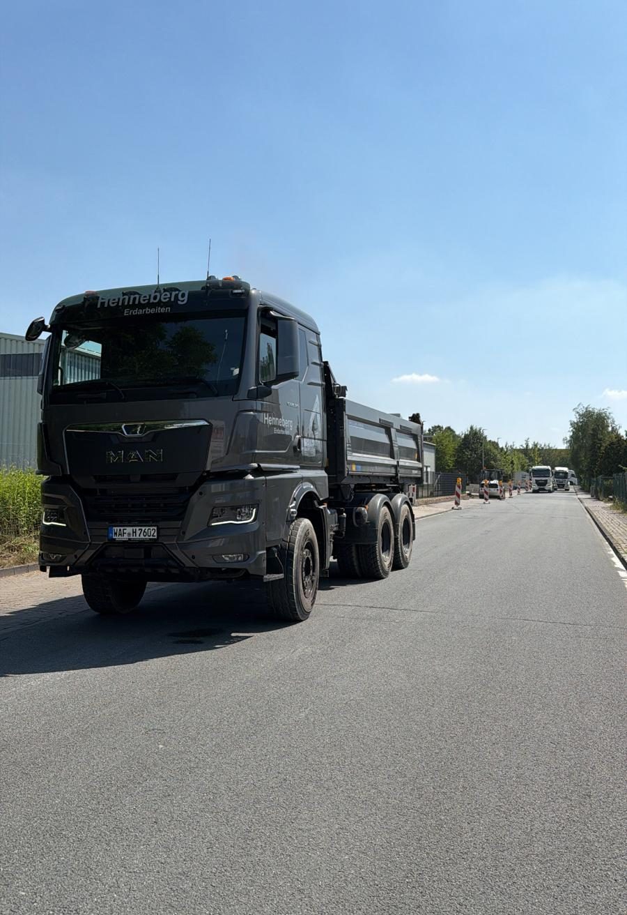 MAN TGX von Henneberg Erdarbeiten mit Mulde auf der Straße vor einer Baustelle